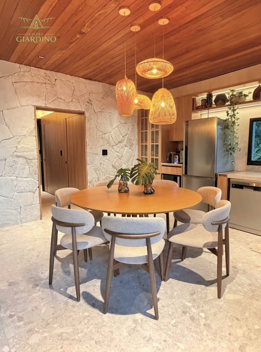 Mesa de jantar redonda em madeira com cadeiras estofadas e luminárias de fibra natural